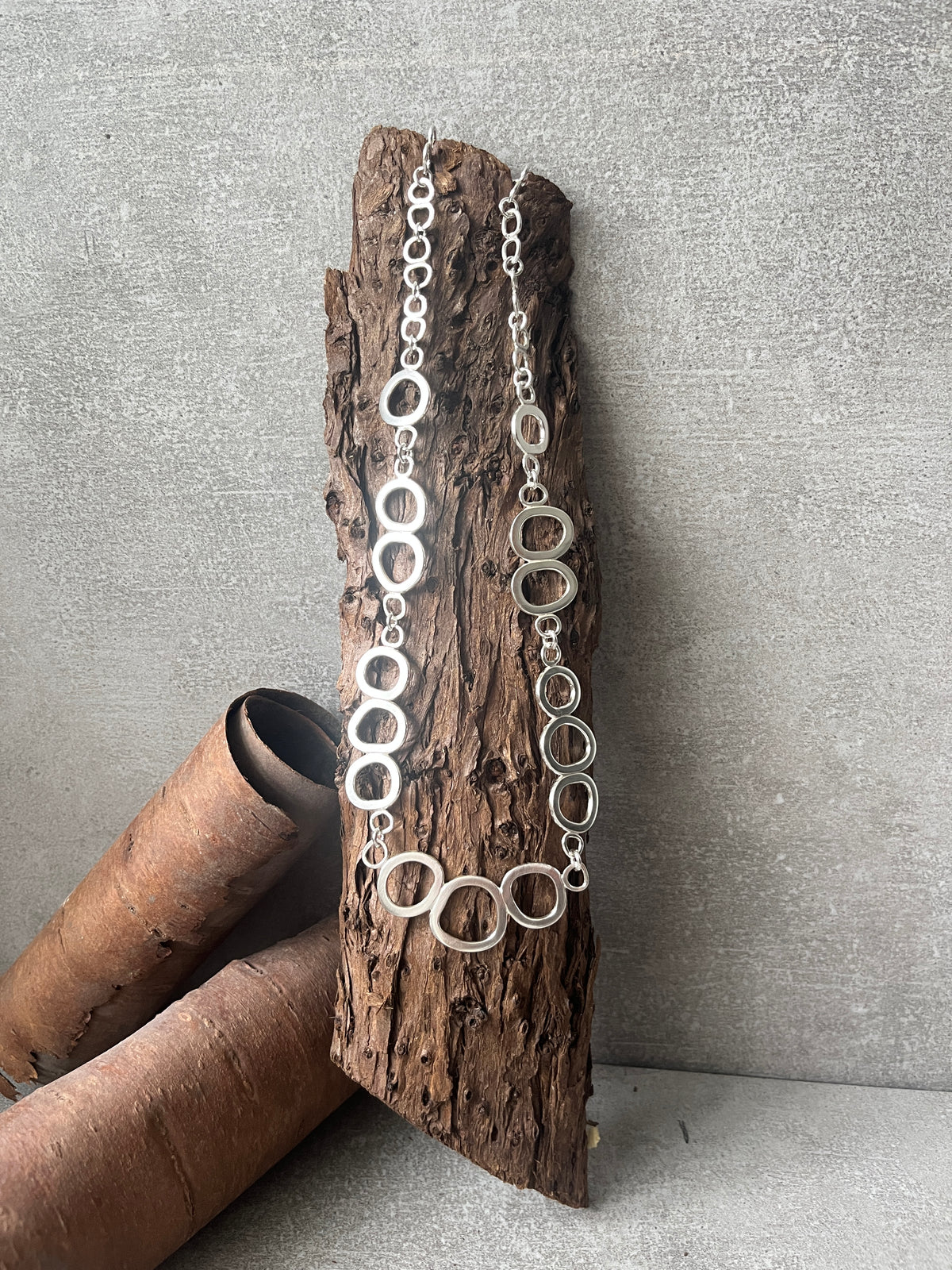 Flowing Elements necklace draped on a sculptural wooden form
